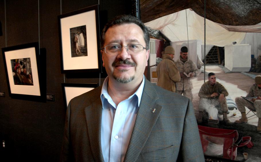 Charles Grow, a retired Marine combat artist who is now deputy director of the National Museum of the Marine Corps, stands in front of some of Staff Sgt. Kristopher Battles' art at the museum in Quantico, Va. Grow says Battles ''has produced a large volume of very high-caliber work ... some of the best in the collection, in my opinion.''