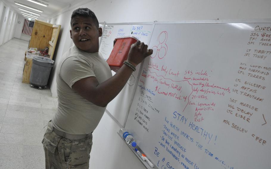 Spc. Steven Miramontes draws a biohazard symbol above the names of soldiers in his unit who've become sick.