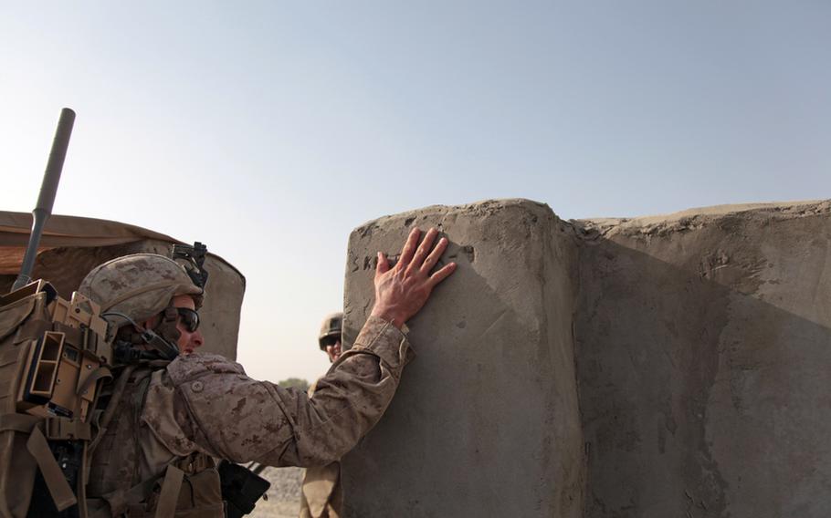 Lance Cpl. Chris Wombaker, a 21-year-old anti-tank assault man from Greenville, Texas, touches a graffito scratched into the cement of the outer wall of Checkpoint 4 in Garmsir district, Helmand province, as he heads out on a patrol with 4th Platoon, Weapons Company, 1st Battalion, 3rd Marines. U.S. casualties fell in September to a five-month low.