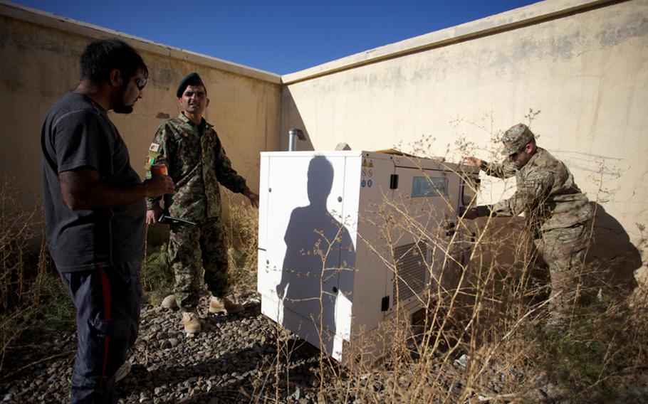 Afghan National Army Sgt. Maj. Neamatullah talks with an interpreter as U.S. Army 1st Sgt. Donald Hansen inspects one of three broken generators on the Afghan base adjacent to Forward Operating Base Bullard in Zabul province's Shajoy district.