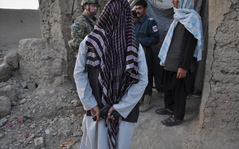 An Afghan NDS agent waits to enter a residential compound during a joint raid by U.S. troops and Afghan security forces in Kandahar City.