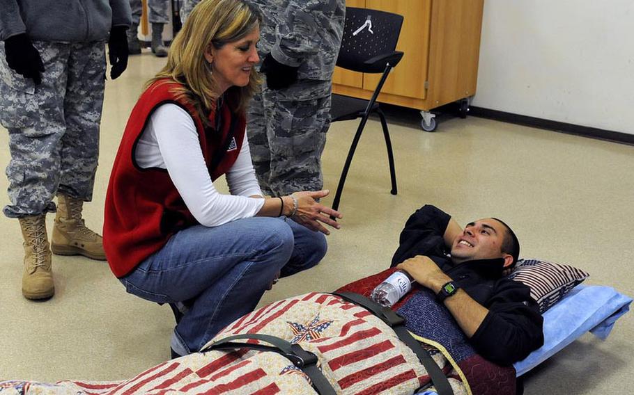 Karolina Wignall, manager for the USO at the 86th Contingency Aeromedical Staging Facility at Ramstein Air Base, talks to Spc. Marcus Ortiz, as he waits for a MEDEVAC flight back to the U.S. Ortiz is resting his head on a donated pillow.