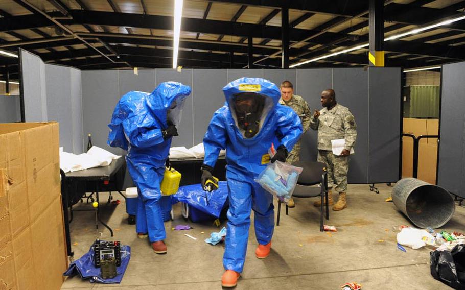Sgt. David Larkin, left, and Staff Sgt. Tim Butler, both of the 773rd Civil Support Team, leave the "contaminated zone" during a training exercise in Kaiserslautern on Dec. 6., as Sgt. 1st Class Jose Mora, left, and Staff Sgt. Kwabena Kyeremeh of USAREUR Emergency Management Assessment Team discuss how they did.