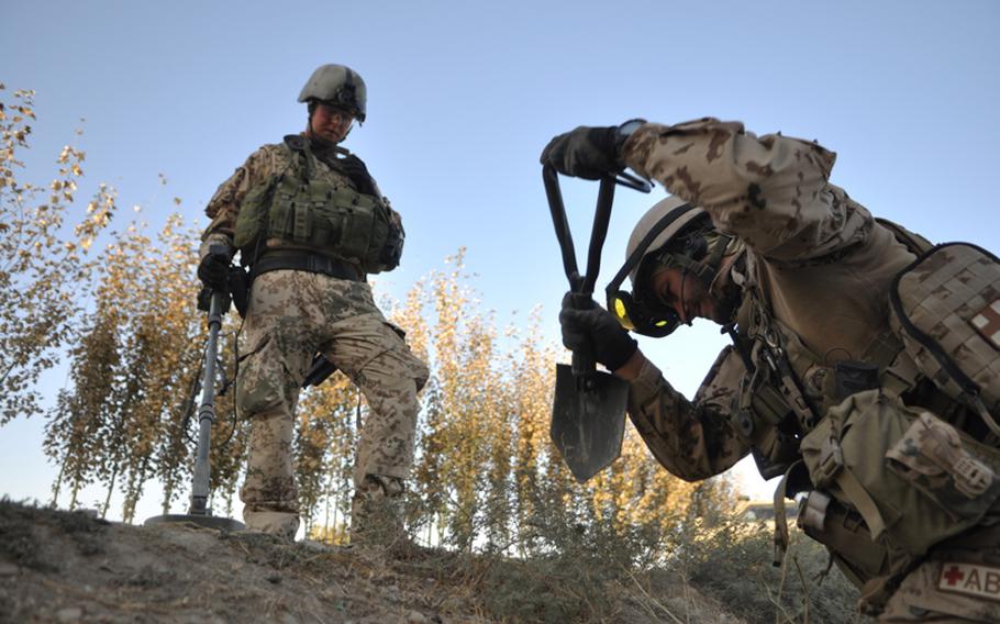 German explosive ordnance disposal soldiers dig for buried bombs along a road in Char Dara district, Kunduz province, Afghanistan. Because the German army doesn&#39;t possess the truck-mounted route clearance equipment the U.S. military uses, soldiers must check and clear by hand, using mine detectors, spades and axes. The going is slow; convoys and troops can move only about 250 yards per hour.
