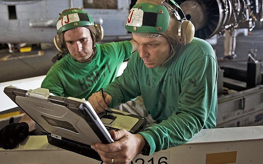 Petty Officer 1st Class Marcus Campagna refers to schematics before installing an engine into an MH-60R Sea Hawk helicopter on the carrier USS John C. Stennis. Ever-changing technology of computer-assisted design programs can wreak havoc with the engineering documents related to the military's vehicles and weapons systems. The documents are constantly merged into the latest CAD software and the conversion process can introduce potentially disastrous inconsistencies.