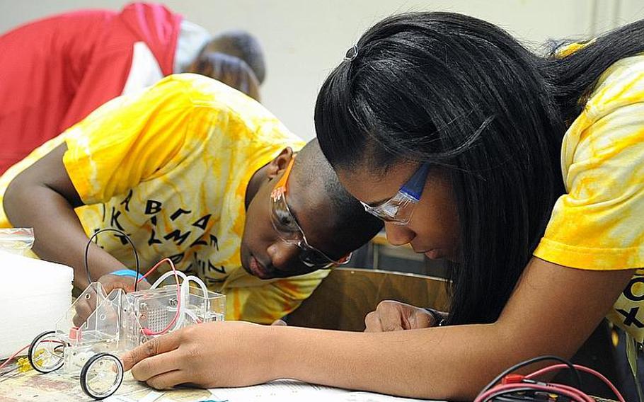 Naples, Italy, freshman Kenan Tukes, left, and Vicenza, Italy, 10th-grader Quatia Bradshaw work on their hydrogen-powered car at STEMposium, DODDS-Europe's first conference designed to introduce students to a real-world scenario that presents problems requiring the application of science, technology, engineering and math to solve. The pair were members of the Green Tech group.