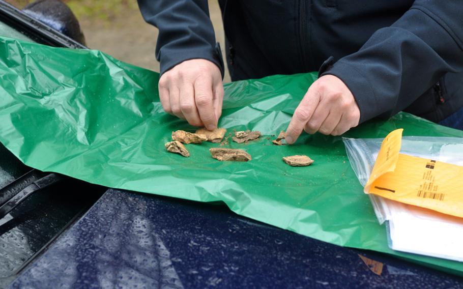 Boeblingen Police Detective Rainer Schaber, on April 5, 2012, inspects bone fragments found by U.S. metal detector enthusiasts at what is believed to be a World War II crash site near the town of Grafenau, Germany.