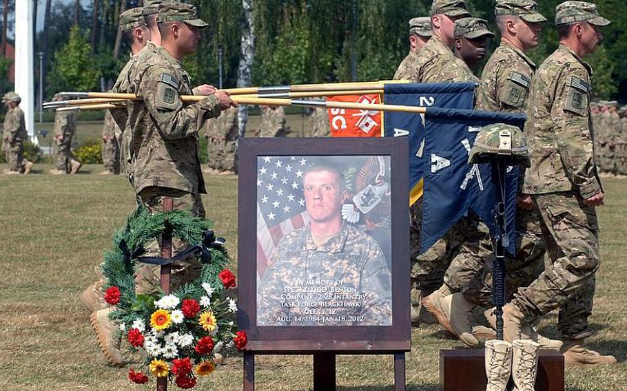 Soldiers on review pass behind the framed photo Spc. Keith D. Benson, one of 10 soldiers from the 172nd Separate Infantry Brigade who died during the unit's 11-month deployment to eastern Afghanistan. The brigade, which returned in July, uncased its colors during a ceremony Thursday in Grafenwöhr, Germany.