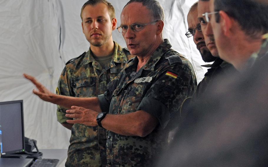 German Air Force Col. Gernot Kopf, second from left, of the Extended Air Defense Task Force, asks a question during a tour of the new mobile tactical operations center of the 10th Army Air and Missile Defense Command at Rhine Ordnance Barracks in Kaiserslautern on Aug. 28, 2012.