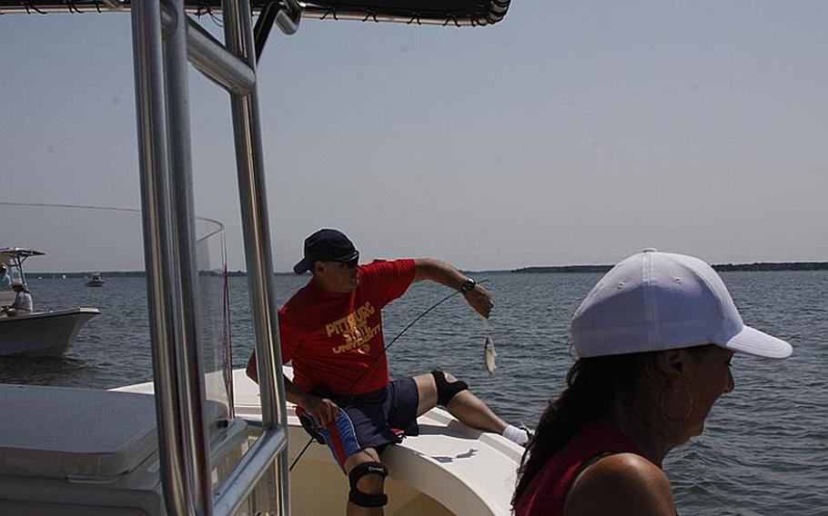 Sgt. Maj. Angel "Tony" Alvarez reels in a striped bass, while his wife, Ivana, fishes off the side of the boat during last month&#39;s Stars and Stripers fishing tournament in Chester, Md., sponsored by Project Healing Waters. The group promotes fishing, usually fly fishing, as therapeutic recreation for veterans with physical and psychological wounds.
