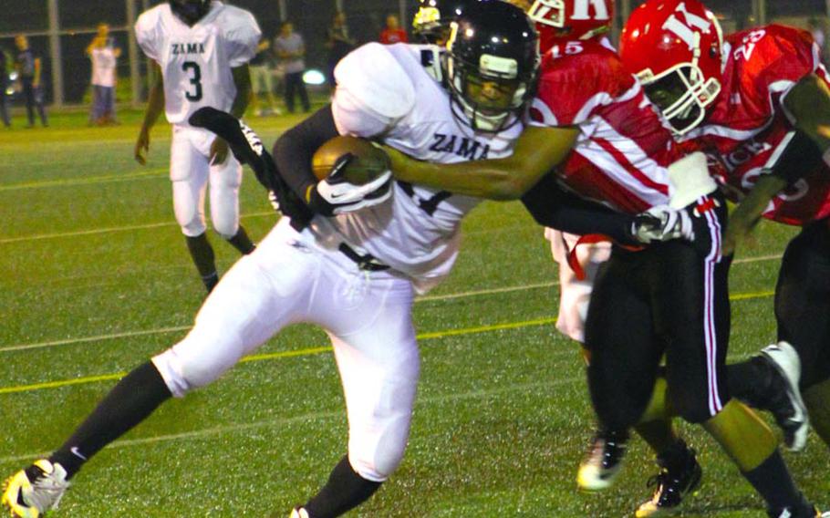Zama American Trojans running back Mitchell Harrison gets tackled by Nile C. Kinnick defender Alex Banks during Friday's DODDS Japan-Kanto Plain Association of Secondary Schools football game at Yokosuka Naval Base, Japan. Harrison scored a touchdown in his first game back after shoulder surgery, and the Trojans rallied to beat the Red Devils 14-13.