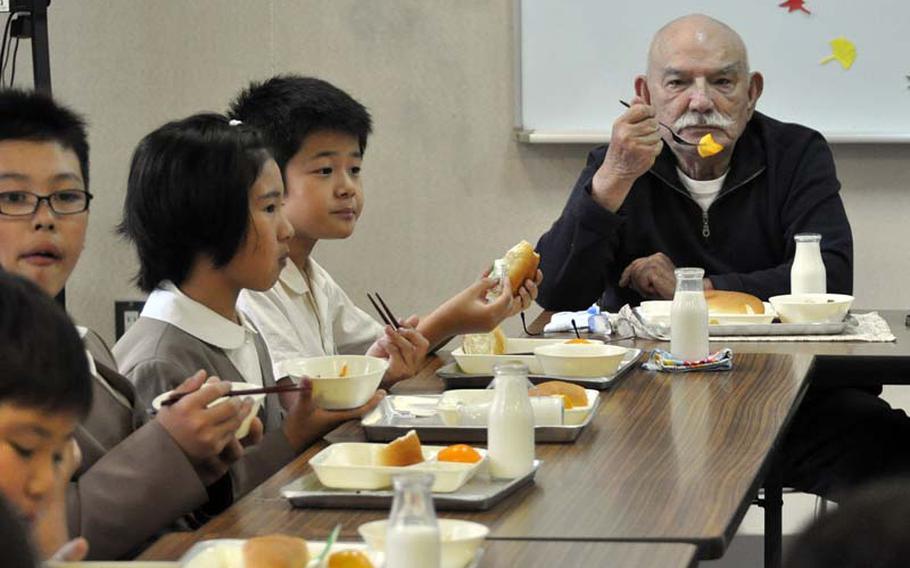 George Summers, a former POW in Japan, eats lunch with children at Takami Elementary School near the former Sakurajima concentration camp. The students asked Summers and two other former POWs questions about war and the atom bomb. "War is the curse of the world," Summers told them.