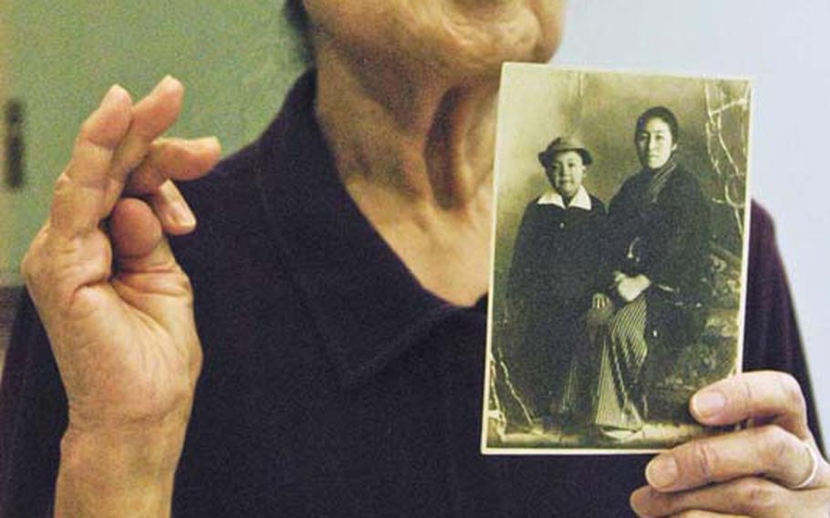 Osaka resident Takao Iga, 79, displays a photo of her mother and her younger brother who were killed during one of several Allied firebombings of Osaka in 1945, while talking a group of American ex-POWs at Osaka International Peace Center on Oct. 18, 2012. Iga and the men recounted similar stories of the destruction that engulfed Osaka during the last few months of the war.