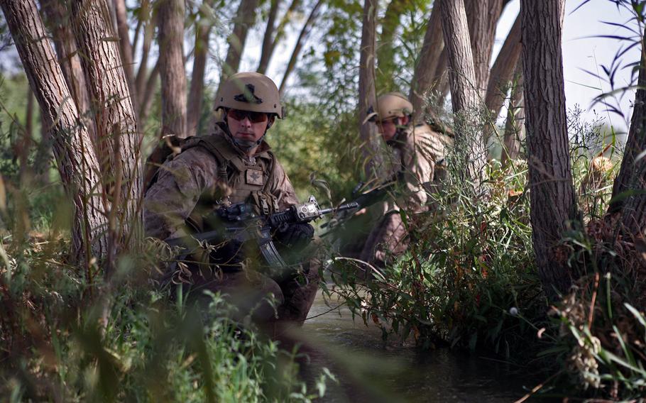 Lance Cpl. Dustin Thompson, a radio operator with Firepower Control Team Alpha, 1st Brigade Platoon, 2nd Air Naval Gunfire Liaison Company, Marine Expeditionary Brigade-Afghanistan, sits in an irrigation canal with Cpl. Tim Barney, a forward observer with FCT-A, during a patrol, Sept. 23, 2009, near Checkpoint North in Helmand province, Afghanistan. The patrol took the soldiers and Marines through fields of crops and through waist-high irrigation canals from the checkpoint down to another U.K. post known as Tapa Parang and back up to the checkpoint.
