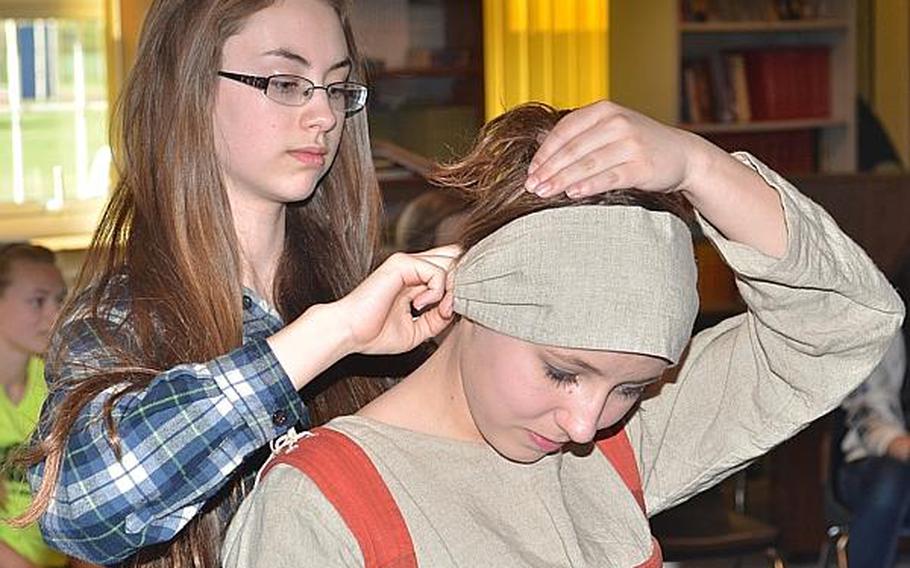 Alyssa Spalinger, an eighth grader at Lakenheath Middle School, helps fellow eighth grader Nicolette Gaboriault-Whitcomb out of 16th century reproduction clothing she donned over her school clothes during a presentation about the life of common people at the time. The presentation was part of UK Day, an annual event sponsored by the Parent Teacher Organization, Friday, May 3, 2013.