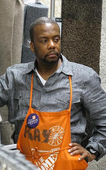 A man wearing a Home Depot apron poses for a photo