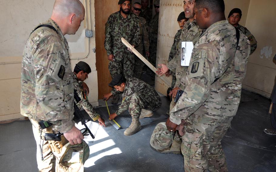 Members of the 859th Engineer Company (Vertical) watch as Afghan National Army soldiers install flooring as part of the final stages of a joint construction project at the ANA's 4th Brigade headquarters near Jalalabad, Afghanistan.