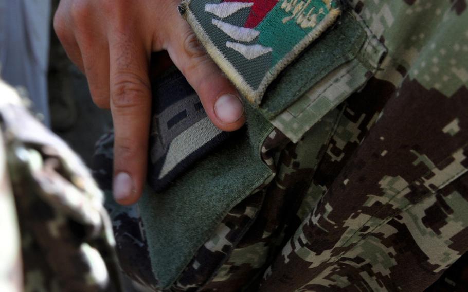 Afghan National Army Sgt. Sarar Wali attaches a patch he received from members of the U.S. Army 859th Engineer Company (Vertical) after a joint construction project at the ANA's 4th Brigade headquarters near Jalalabad, Afghanistan. U.S. soldiers hope such project will help build better facilities, and better relationships with Afghan troops.