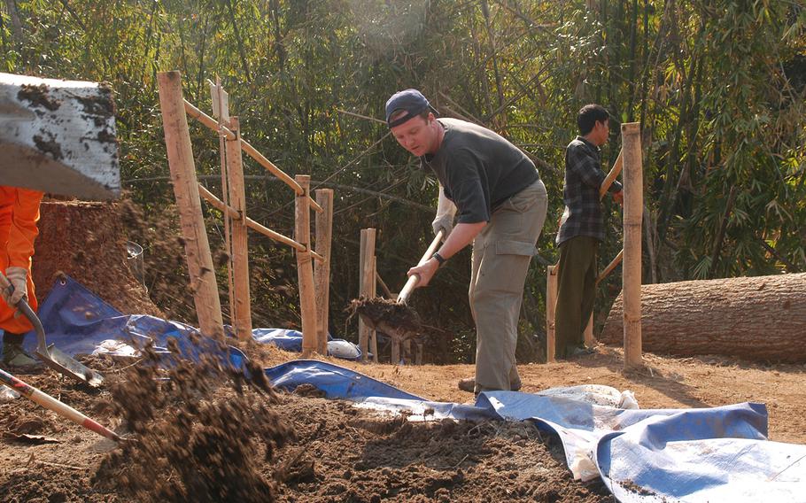 A member of the Joint POW/MIA Accounting Command searches for clues of remains at a crash site in Myanmar in this undated photo.