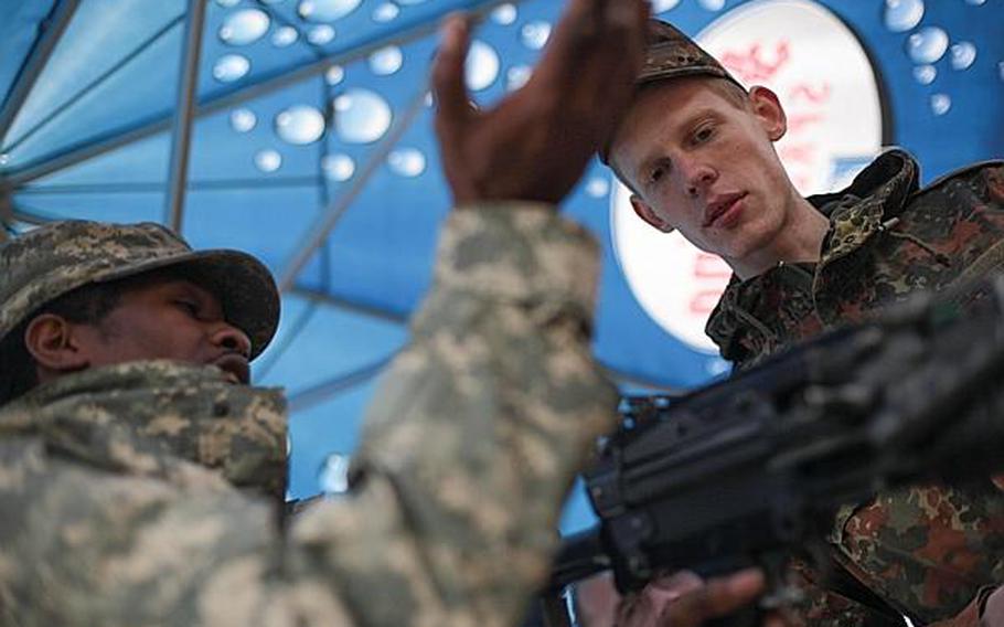 Spc. Arnel Jones of Headquarters and Headquarters Company, 1st Battalion, 214th Aviation Regiment, in Wiesbaden, Germany, explains how to use an American M-249 squad automatic weapon to a German competitor at the Monte Kali shooting competition Friday in Wackernheim, Germany. Matt Millham/Stars and Stripes