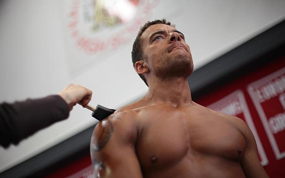 Army Sgt. 1st Class Christopher Headley from Stuttgart, Germany, gets "painted up" before competing Saturday in the 2013 Bodybuilding and Figure Invitational in Kaiserslautern.