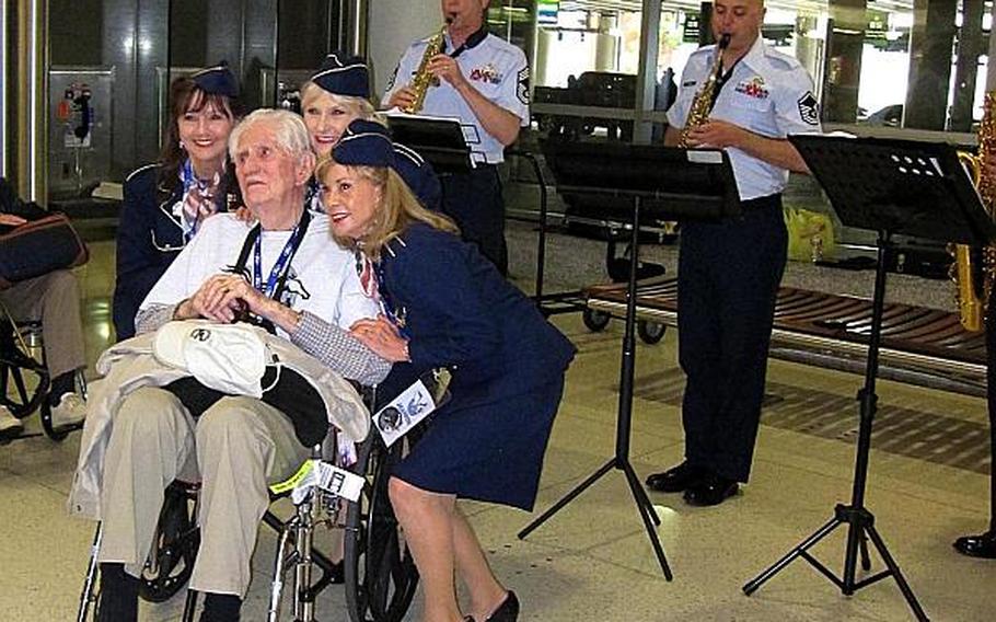 Mr. Herd with the Ladies for Liberty, who traveled with him on the trip and entertained the veterans in the airports, on the planes and on the bus ride. They are posing with him as an Air Force band plays military tunes and other tunes from the 40s.
