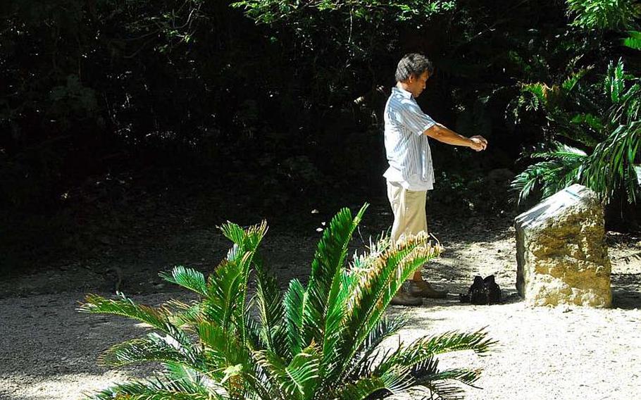 A visitor photographs an historic plaque in the prayer garden of the Sefa Utaki holy site.