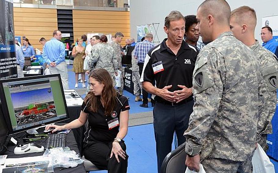 As Jessica Durst demonstrates, Rick Racine of BAE Systems explains to Spc. Jerry Akins and Sgt. Ken Pehoski how the company's GXP Xplorer works at the technology expo at Clay Kaserne in Wiesbaden, Germany, Friday, July 26, 2013. More than 50 exhibitors showed their goods at the expo, which focused mostly on communications and security. The GPX Xplorer is a management application for geospatial data.