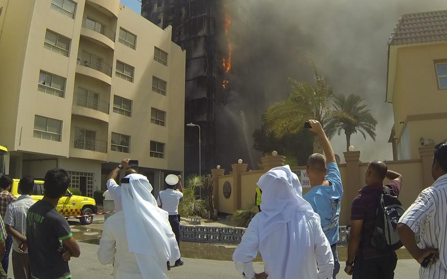 Bystanders watch as Bahrain's Civil Defense firefighters douse a burning apartment building in Juffair Tuesday morning, Aug. 27, 2013. The building is located yards from the Naval Support Activity fence line.
Hendrick Simoes/Stars and Stripes