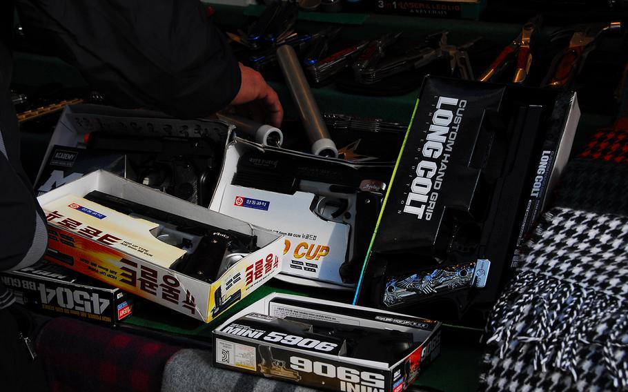 A sidewalk vendor in Itaewon arranges a display of BB guns, scarves and other mock weapons, not far from the spot where three U.S. soldiers allegedly fled after at least one of them shot a BB gun at passersby in early March.