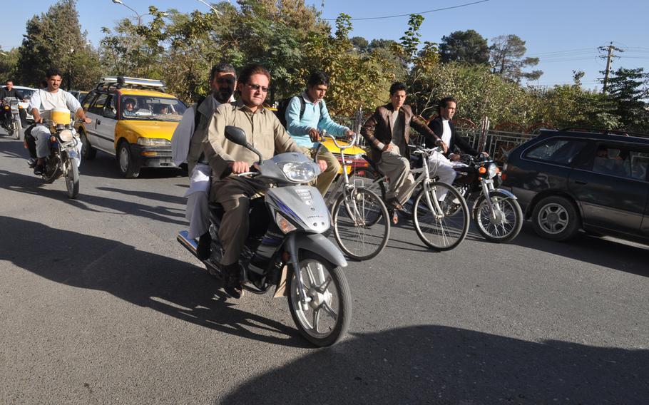 Traffic in Herat, Afghanistan, where pedestrians dodge cars and speeding motorcyclists.