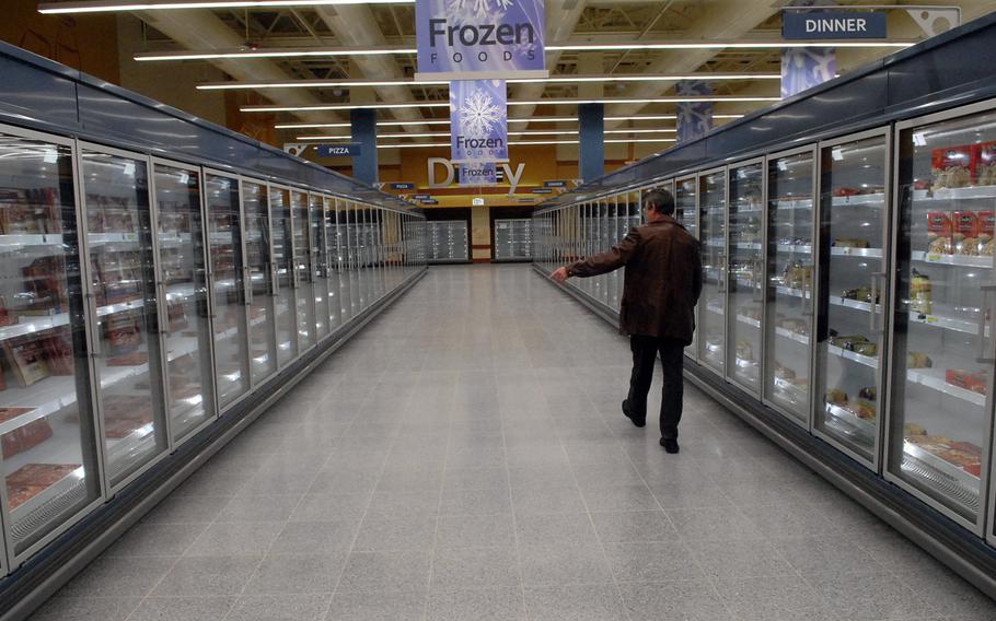 The renovated Ramstein Commissary has an expanded frozen foods section and wider aisles, among other features. Harry Nichols, the store's director, shows off the space where shelves are already stacked with frozen pizza and other items.