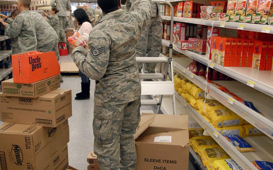 Air Force Staff Sgt. Raymond Hart, left, hands boxes of rice to Air Force Master Sgt. Johnnie Grove inside the newly remodeled Ramstein commissary. Hart and Grove were among 27 airmen from the Deployment Transition Center at Ramstein who volunteered to help stack shelves inside the remodeled store Tuesday. The store is scheduled to open Nov. 15.