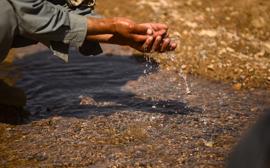 An Afghan police member washes his hands in a farmer's well located in the desert of southern Afghanistan's Zhari district on Oct. 21, 2013.