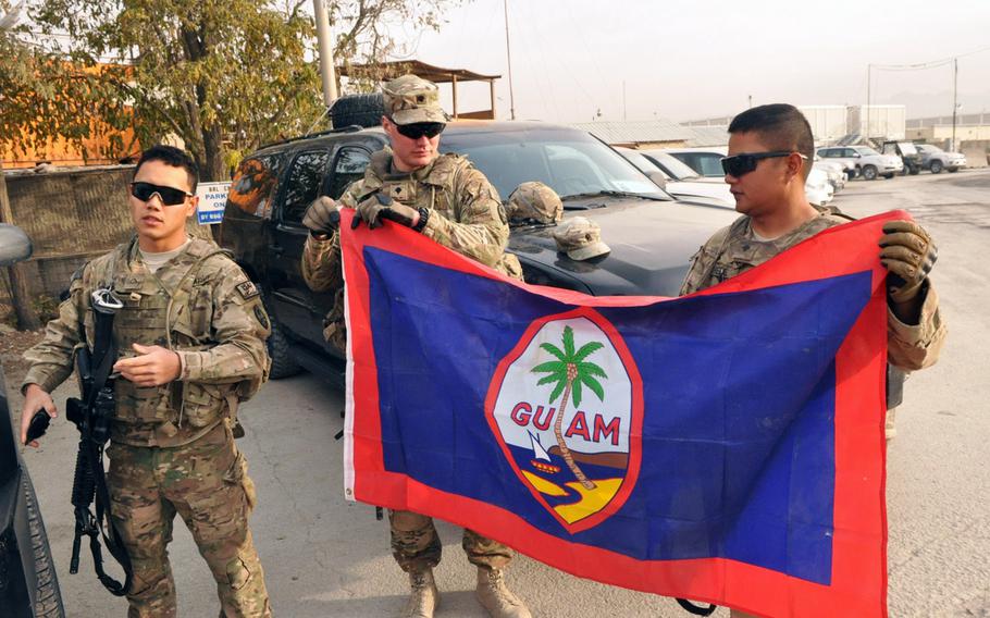 Pvt. 1st Class Raymond A.L. Dulla, left, and Spc. Thomas Clark, center, hold the flag of Guam before a guardian angel mission in Kabul.