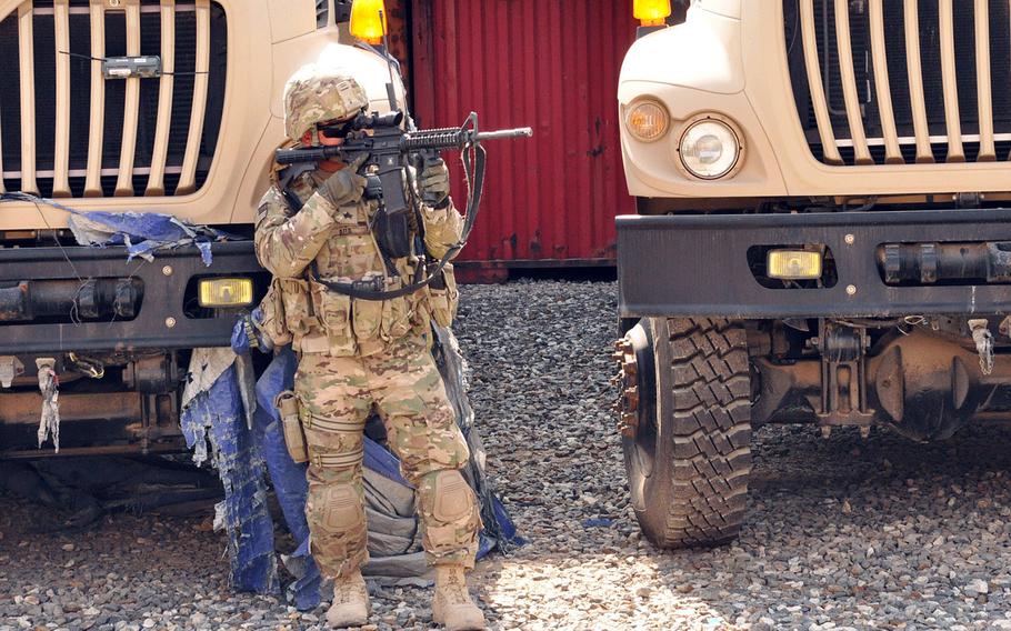 Truck commander Sgt. Billy J. Ada uses his rifle to scout out the area inside the Afghan National Army's Central Issuing Facility after a bullet from an unknown shooter whizzed by a group of U.S., Afghan and Australian soldiers. Ada was on a guardian angel mission to protect a lieutenant colonel who was at the issuing facility to assist the Afghans with logistics. Ada suspected it might have been an accidental discharge from the AK-47 of an Afghan Army soldier in the area. No one was injured.
