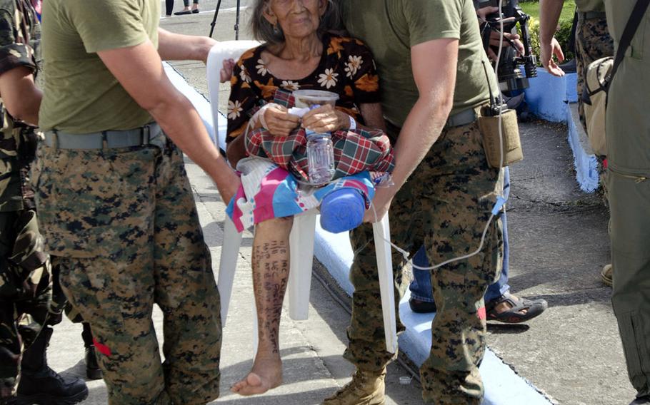 Two U.S. Marines assist a typhoon victim with a freshly amputated leg to safety at Villamor Airbase in Manila, Philippines, November 15, 2013.