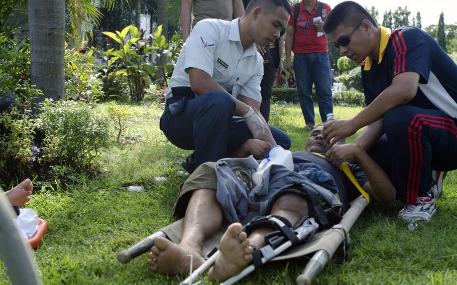 Rescue workers give water to a typhoon victim with a broken leg at Villamor Airbase, Manila, Philippines, November 15, 2013.