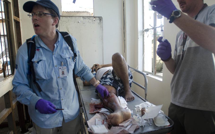 Breaux Burns, a paramedic and former active duty Marine, fills a syringe with a sterile solution to clean a wound as a surgeon clears a patient's infected leg of puss and dead tissue at a field hospital in Tacloban, Philippines. Eric Guzman/Stars and Stripes