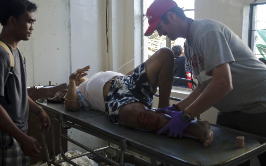 Breaux Burns, paramedic and former active duty Marine, splints a typhoon victim's leg after a surgery in Tacoloban, Philippines. Eric Guzman/Stars and Stripes