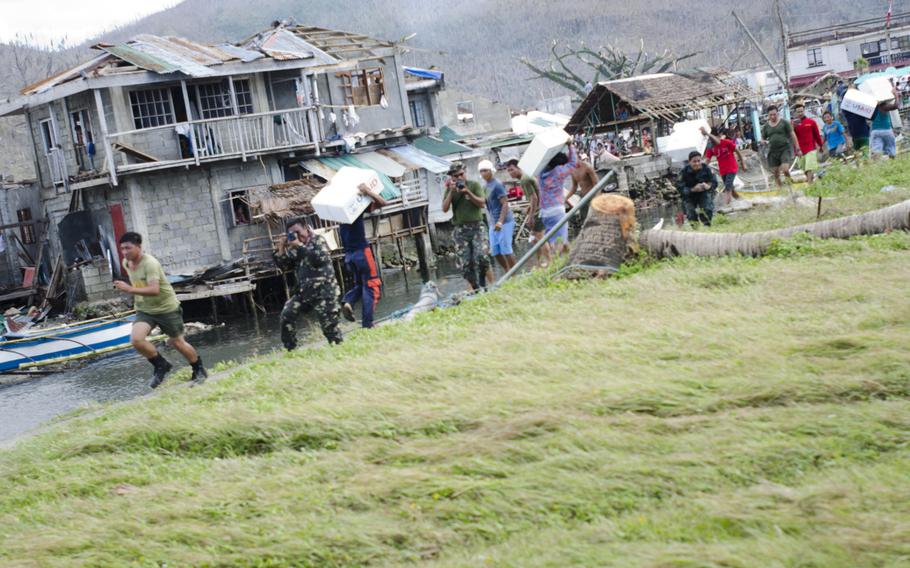 Soldiers from the Philippine Army help victims of Super Typhoon Haiyan retrieve relief packages from a V-22 Osprey in Marabut, Philippines, Nov. 18, 2013.