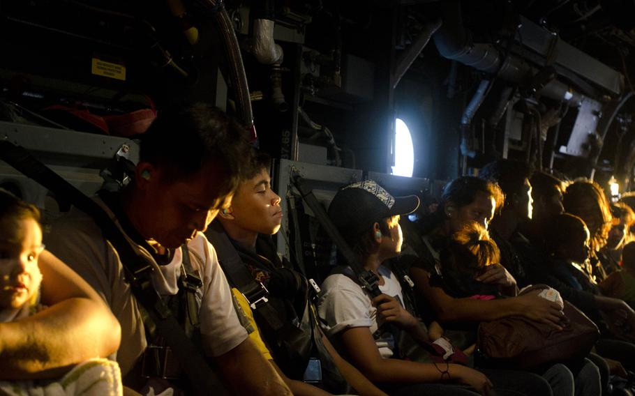 Victims of Super Typhoon Haiyan wait for a V-22 Osprey to lift off and deliver them to an evacuation center located at Manila, Philippines, Nov. 18, 2013.