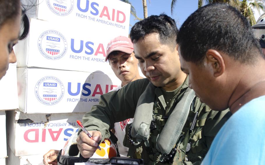 Capt. Adrian Evangelista, pilot, and Allan Naputo, village chairman, speak after boxes of relief supplies were dropped off near Calasi, Philippines, Nov. 18, 2013.