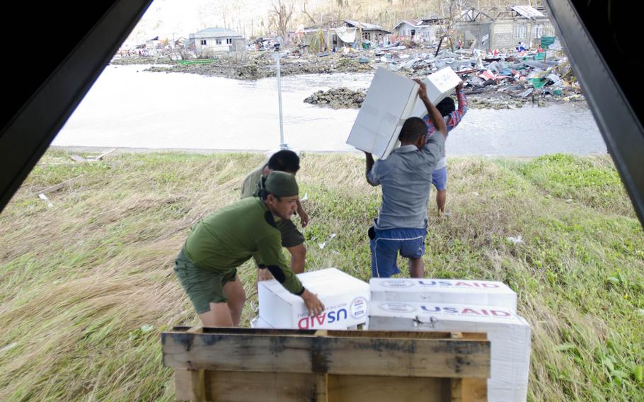 Soldiers from the Philippine Army help victims of Super Typhoon Haiyan retrieve relief packages from a V-22 Osprey in Marabut, Philippines, Nov. 18, 2013.