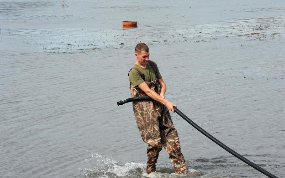 Marine Lance Cpl. Richard Frederick from the 9th Engineer Support Battalion moves a raw water purification pump hose to allow for easier flow of water to the purifier. Marines have purified more than 100,000 gallons of water for use by Typhoon Haiyan victims.