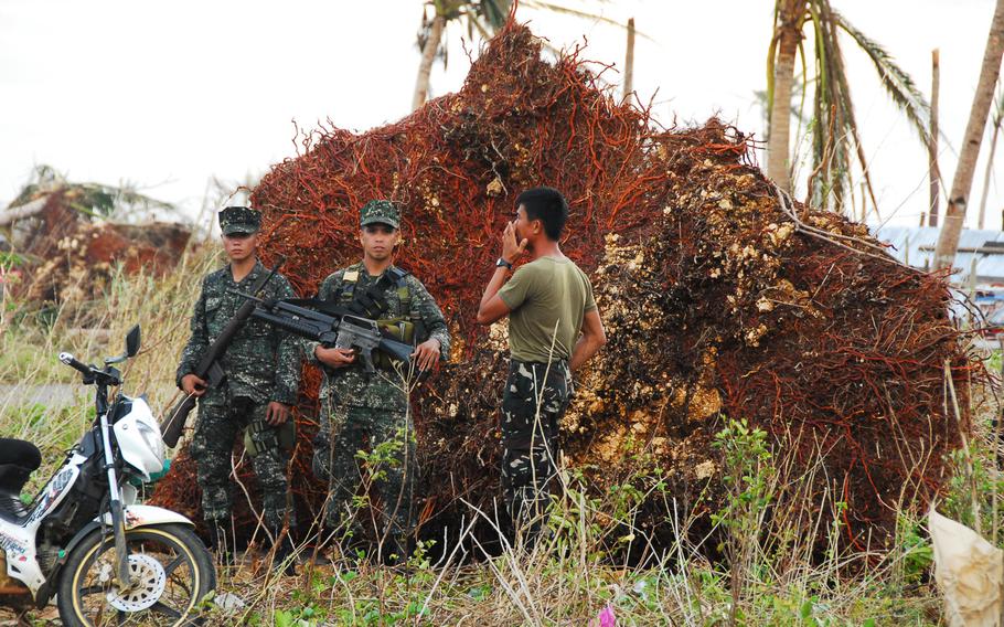 Filipino troops stand guard in front of a fallen coconut tree on Nov. 21, 2013. They took over responsibility for security at Guiuan Airport from U.S. Marines this week.
