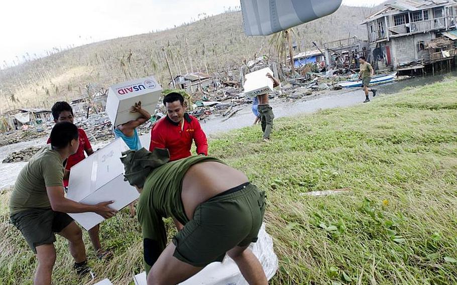 Filipinos unload boxes of relief supplies from a V-22 Osprey at a typhoon-ravaged village last week.