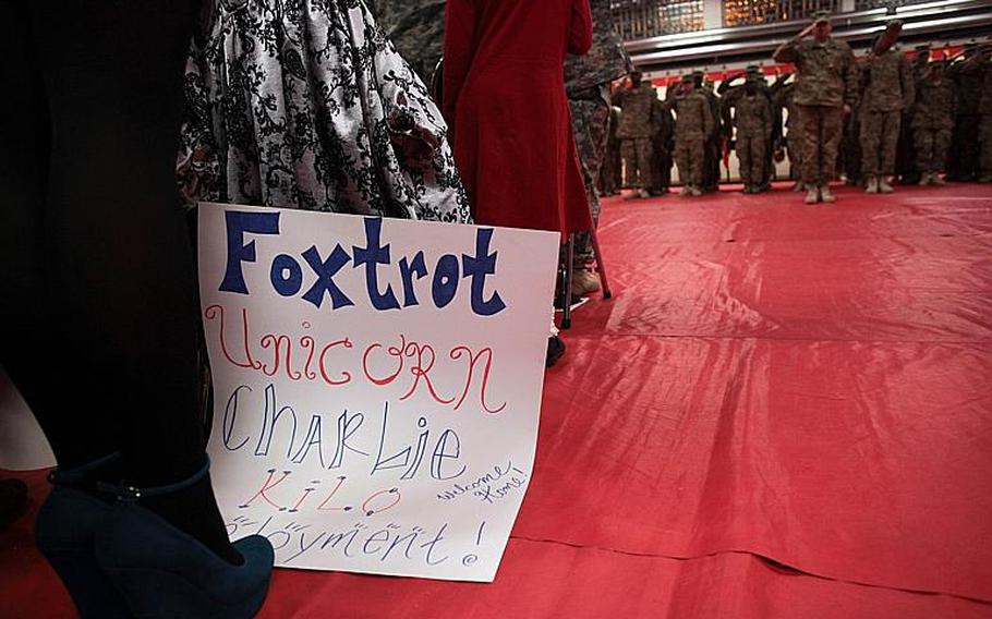 A sight welcoming home soldiers of the 39th Transportation Battalion slumps against a chair while the unit's soldiers salute during the national anthem.
