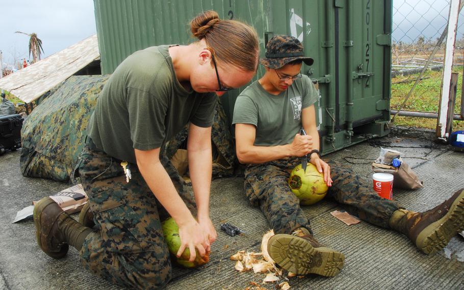 Marine Cpl. Kaycee Morales, 22, of Las Cruces, N.M., left, and Navy Hospital Corpsman 3 Israel Nolen, 20 of El Paso, Texas, work to crack open coconuts during typhoon relief operations in The Philippines on Friday, Nov. 22, 2013.