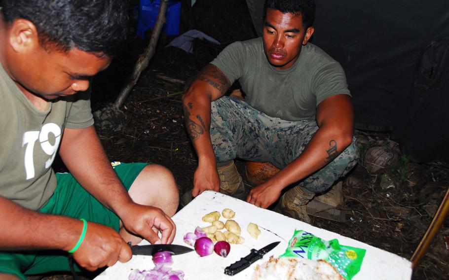 A Filipino airman prepares a meal to share with U.S. Marine Staff Sgt. John Suyat, 32, of Alexandria, Va., on Thursday, Nov. 21, 2013, during typhoon relief operations in the Philippines.